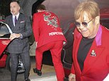 Elton John stands out in bright scarlet suit as he and David Furnish arrivew at swanky members' club