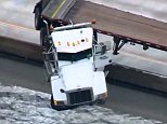 The terrifying moment a semi-truck dangles over the side of a Florida bridge after driver crashes